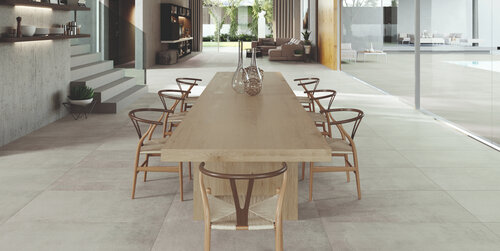 Grossen Haus mit modernen Bodenplatten in hellem grau und einem schönen Holztisch. Die hellen Farben machen der Raum deutlich grösser.