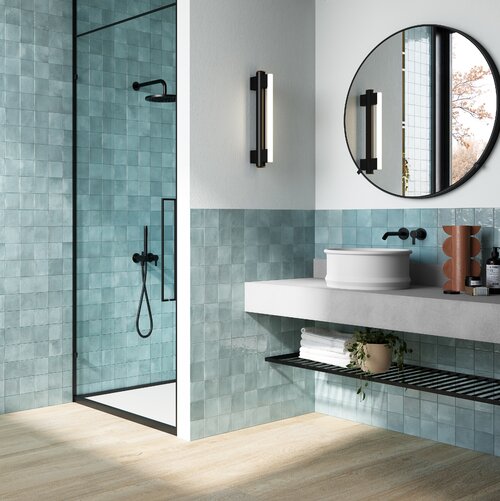 Badezimmer mit kleinen hellblauen Wandplatten und schwarzen Armaturen. Der Boden besteht aus Feinsteinzeug in heller Holzoptik ideal für den Nassbereich.