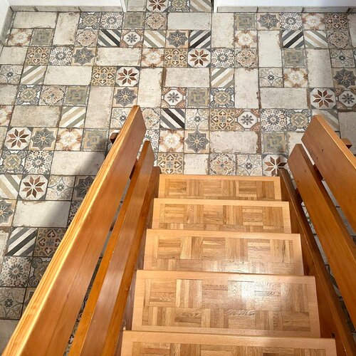 Alte Holztreppe mit neuem Feinsteinzeug Eingangsboden welcher zum Holzton passt. Bodenplatten in mehreren Formaten mit Dekor und weiss modular verlegt.