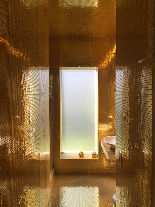 Luxusbadezimmer der Extraklasse. Das Goldmosaik strahlt von Wänden, Böden und Decke im hellen Sonnenlicht.